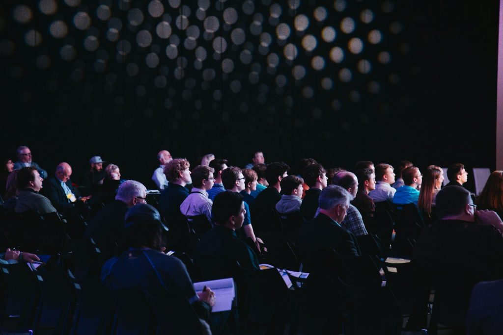 Crowd of people sitting on chairs inside a room