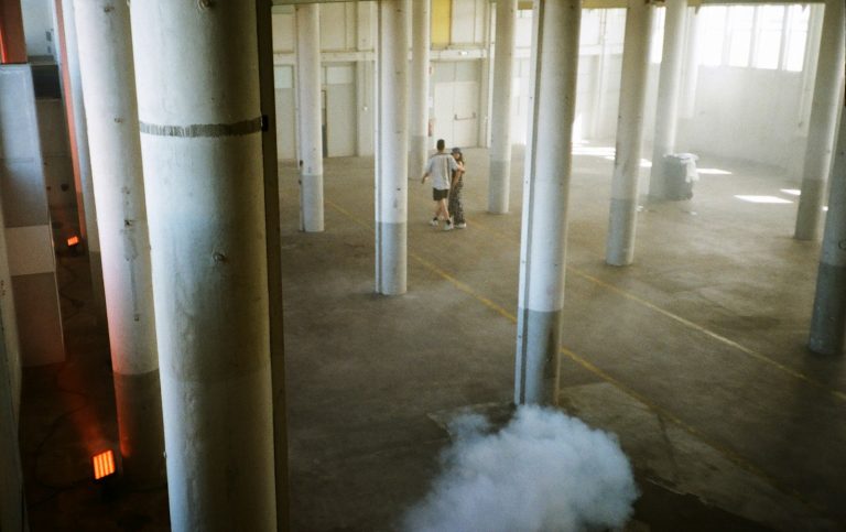 Two people walking through a large empty industrial space